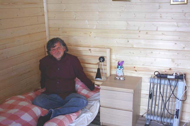 Tommy Schmidt auf dem Bett seines Gartenhauses