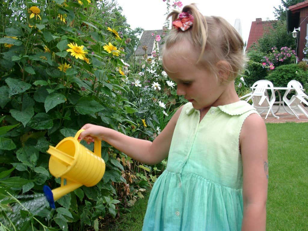 Kind mit Gießkanne im Kleingarten