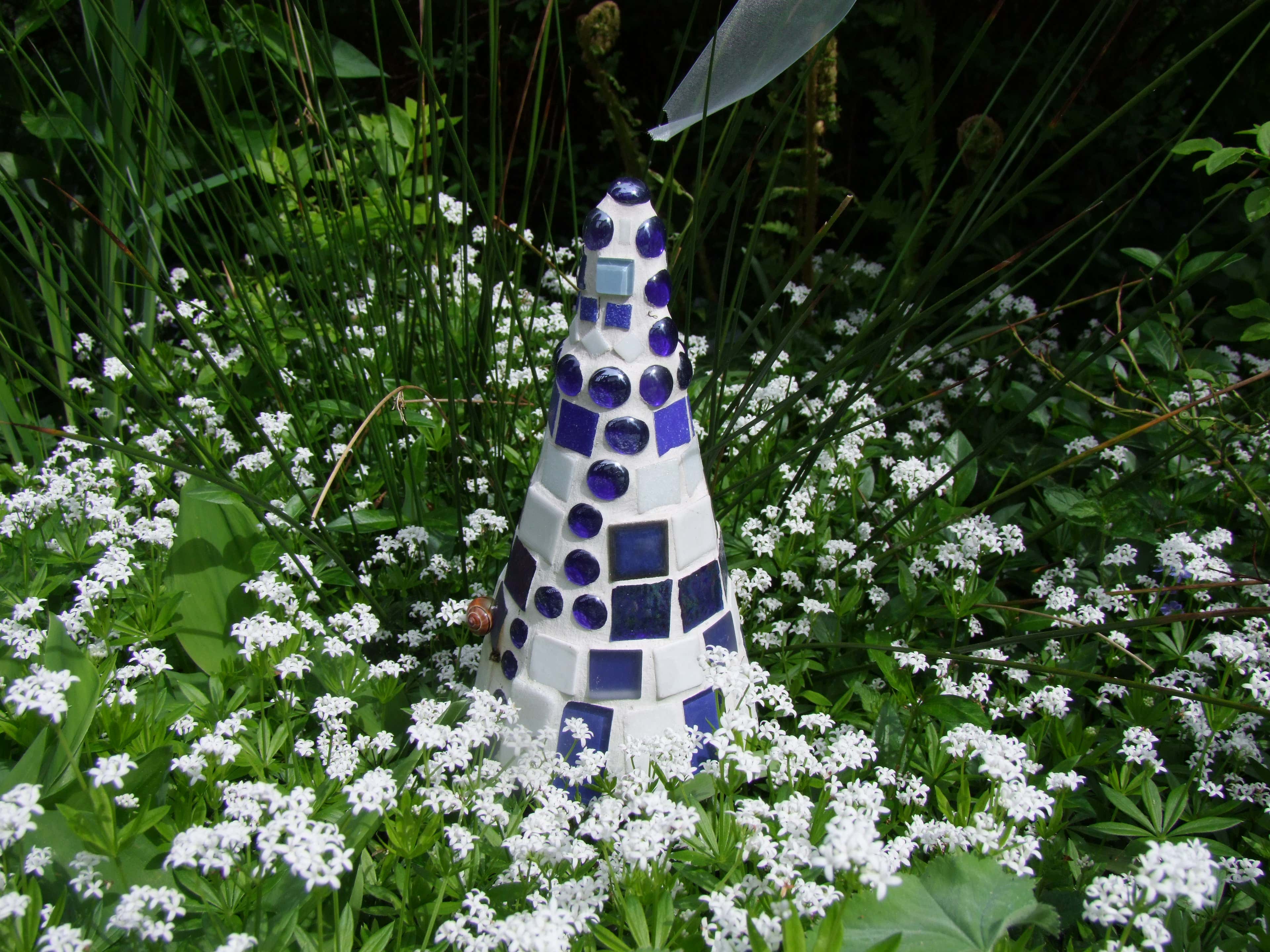 Inmitten einer weißen Blumenpracht: der maritime Mosaik-Leuchtturm.