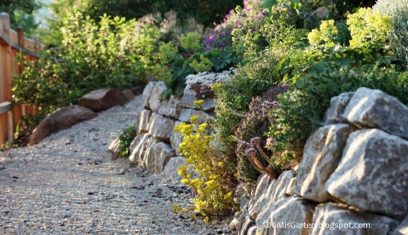 Naturstein-Mauer aus Feldlesesteinen säumt den Gartenweg