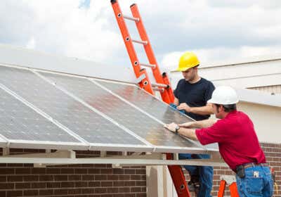 Männer bringen Solarzelle auf Carport an