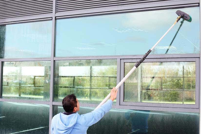 Mann reinigt Fenster Teleskop Stab