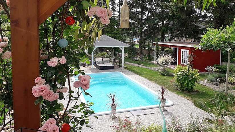Blumen und Pool mit türkisem Wasser und Gartenhaus