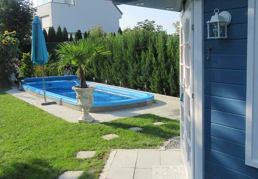 Pool mit blauem Gartenhaus und Sonnenschirm