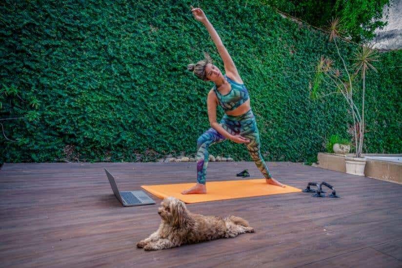 Frau macht Yoga mit Hund und Laptop