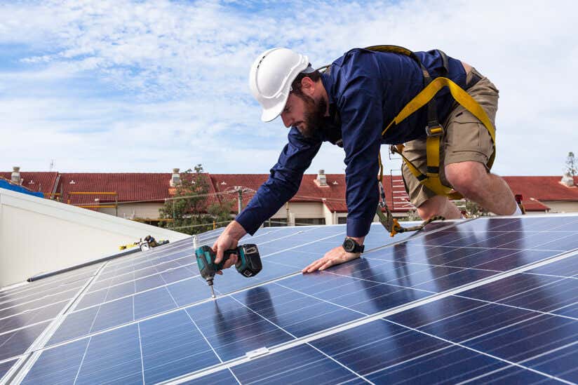 Mann bohrt Solarzelle auf Dach an