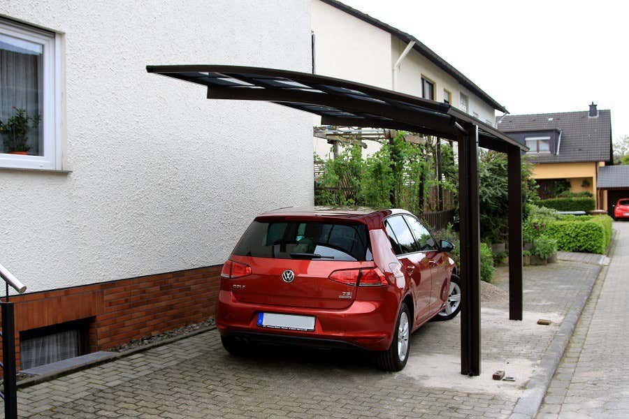 Ein rotes Auto steht unter einem Carport aus Aluminium.