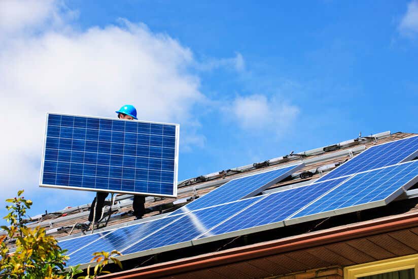 Mann trägt Solarzelle aufs Dach